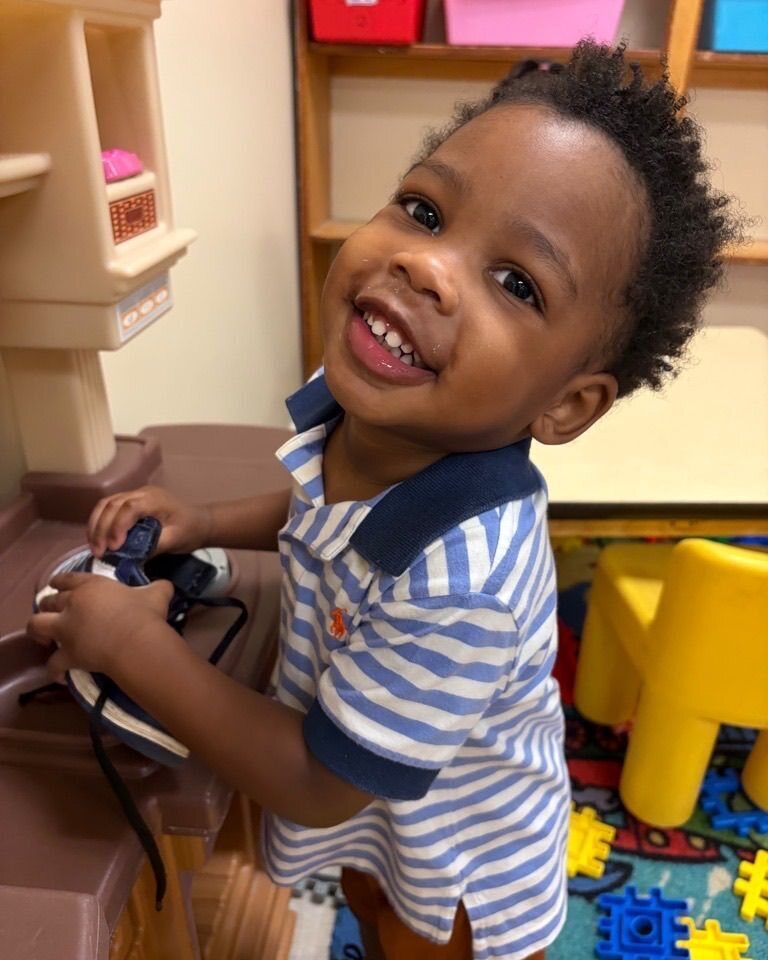 Boy in a striped polo playing at a play kitchen